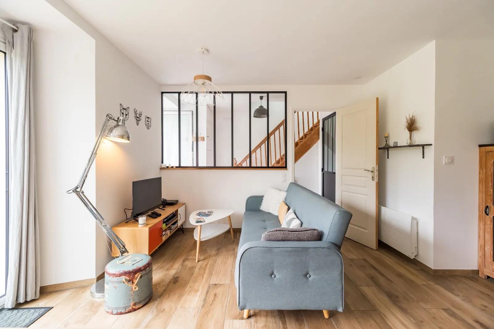Living room with blue sofa, steel-framed glass partition and oak floor